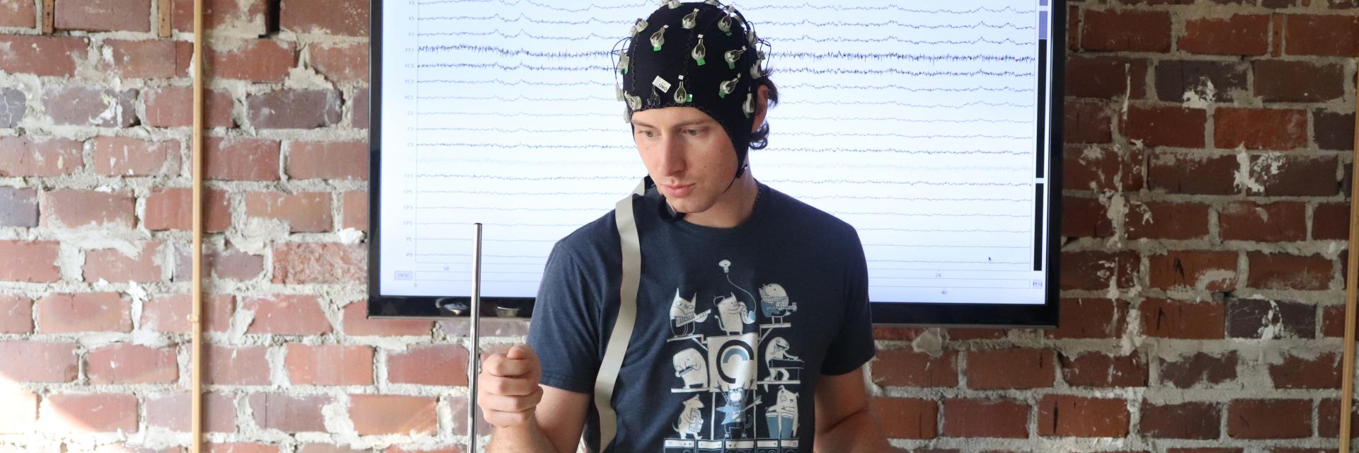 Mike Winters, a Ph.D. student, playing a theramin while wearing a brain scan cap.