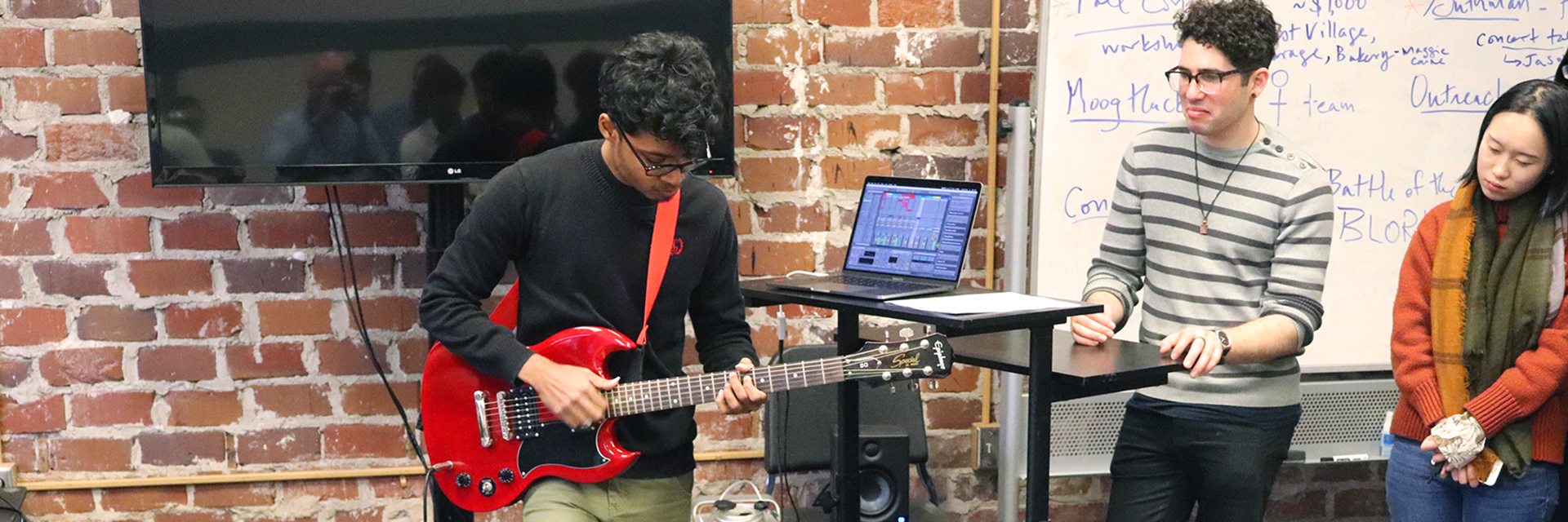A student plays the guitar as part of a project presentation.